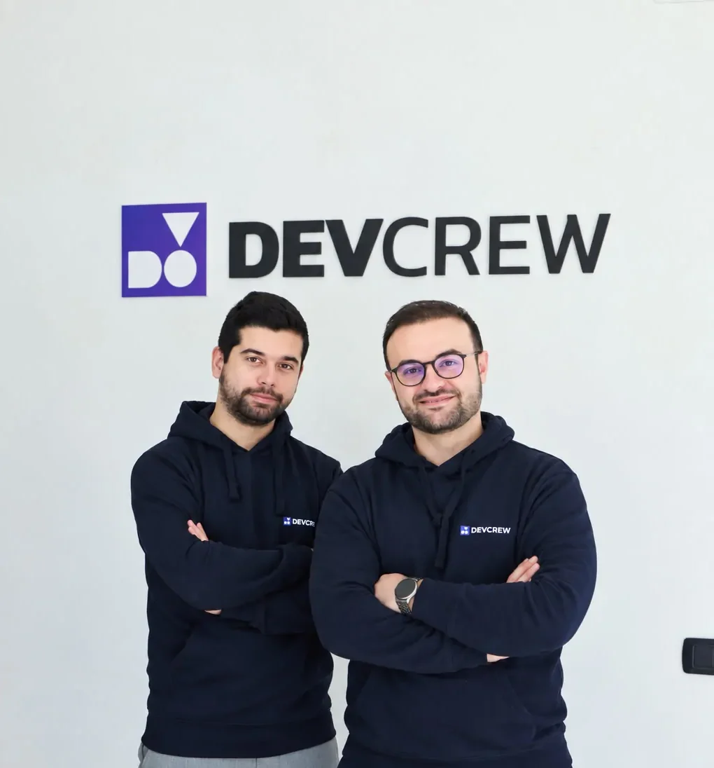 Due sviluppatori del team DevCrew davanti al logo